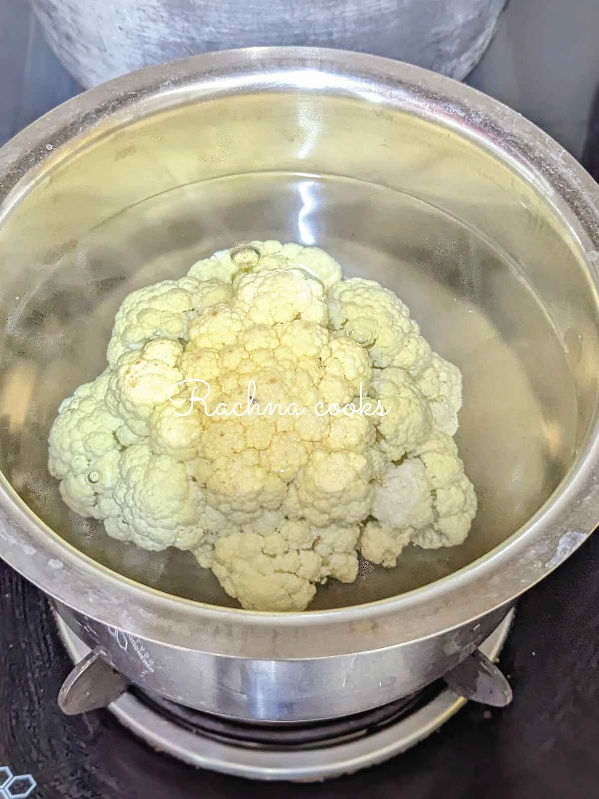 Whole cauliflower immersed in boiling water.