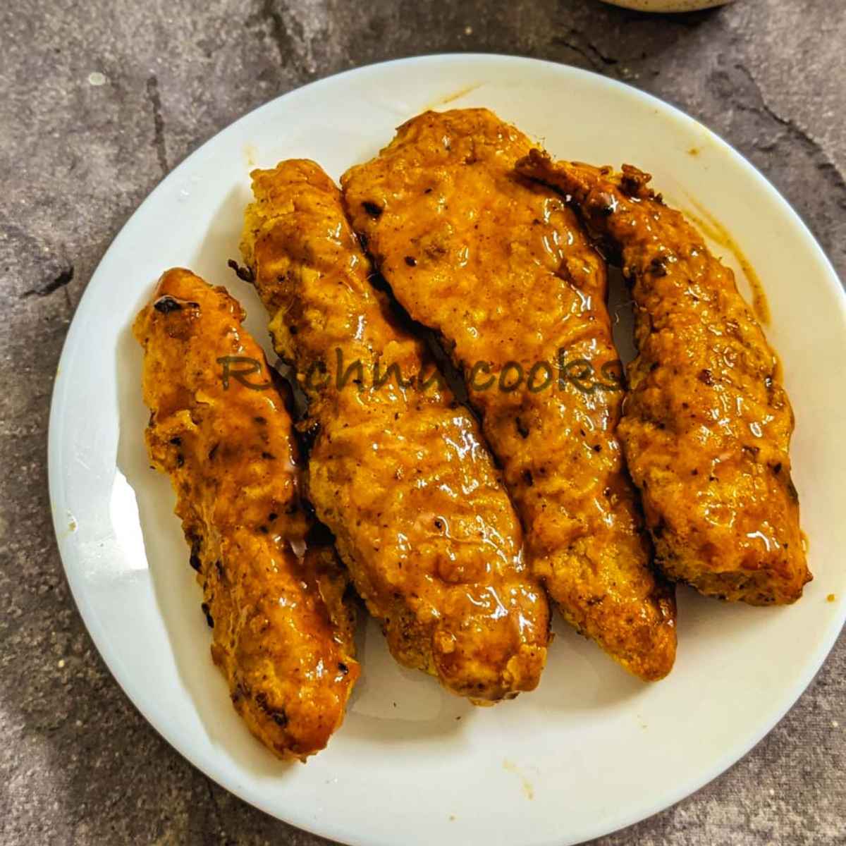 4 air fried crispy buffalo tenders on a white plate.