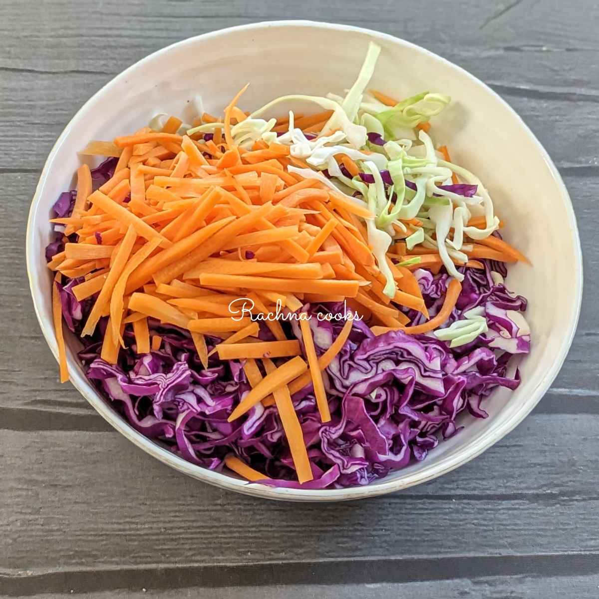 Shredded green cabbage, purple cabbage and carrot and in a bowl