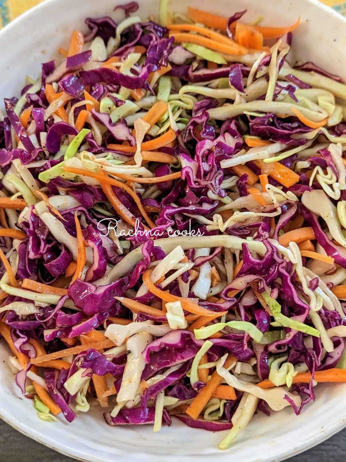 Close up of cabbage and carrot salad served in a large white salad bowl.