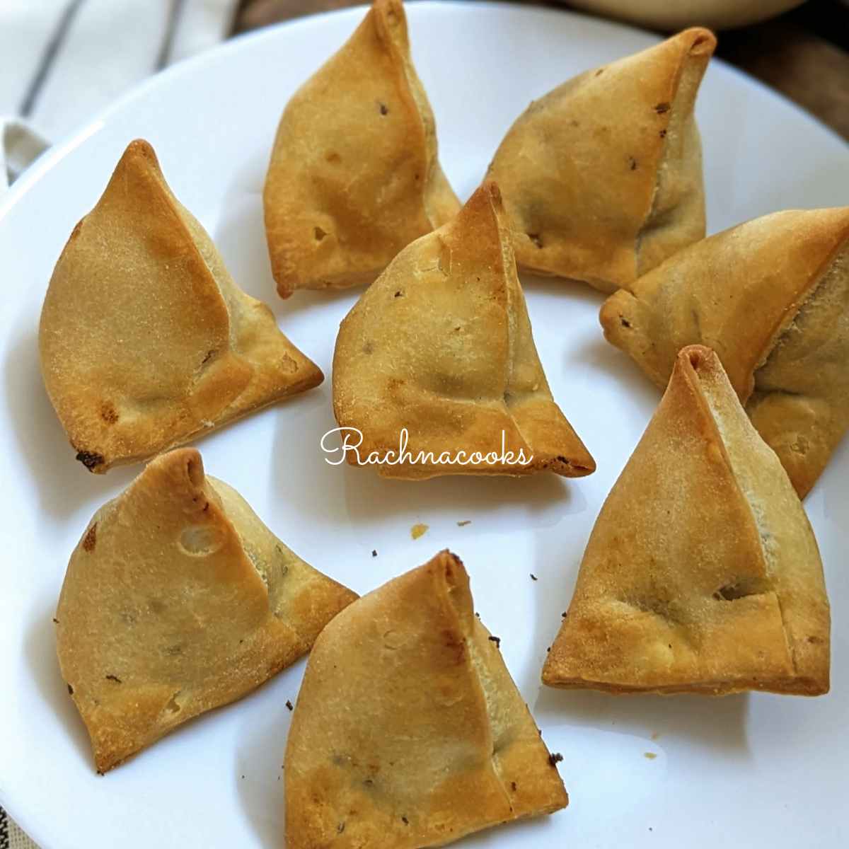 A plate of air fried frozen samosas served on a white plate.
