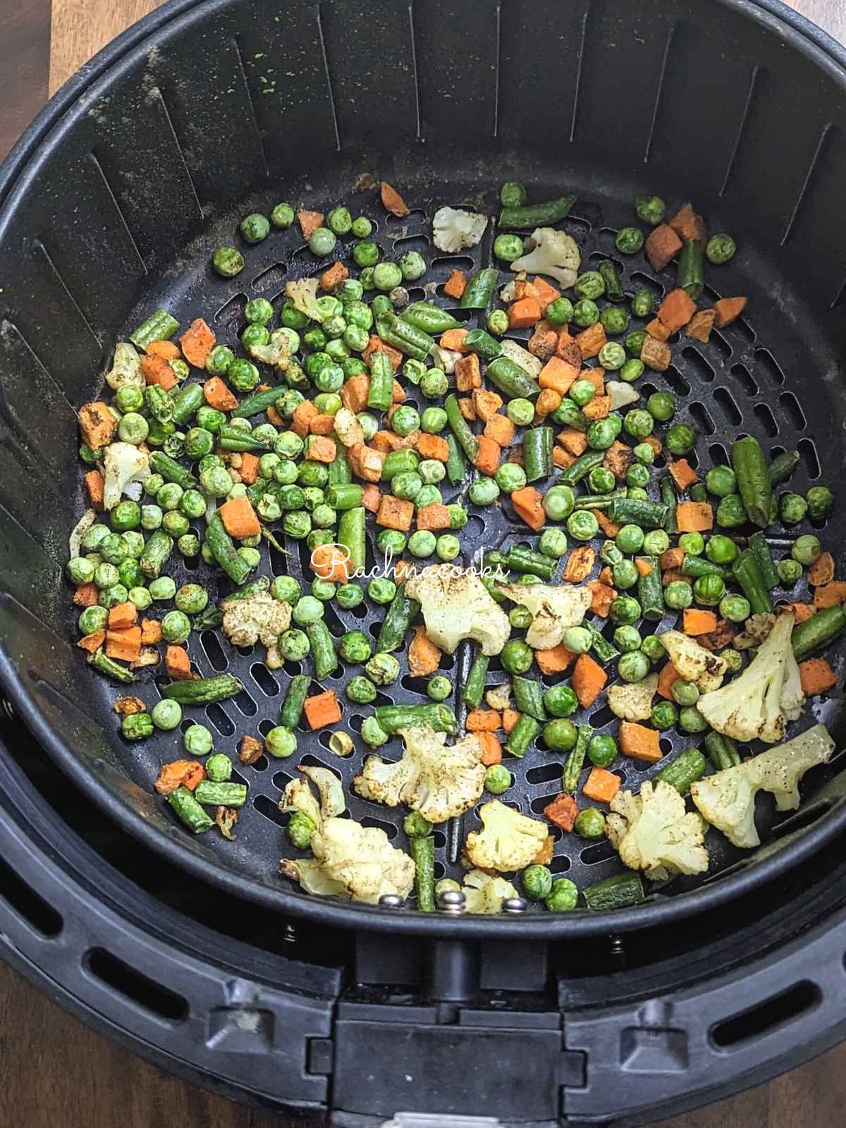 Roasted air fried frozen vegetables in air fryer basket.
