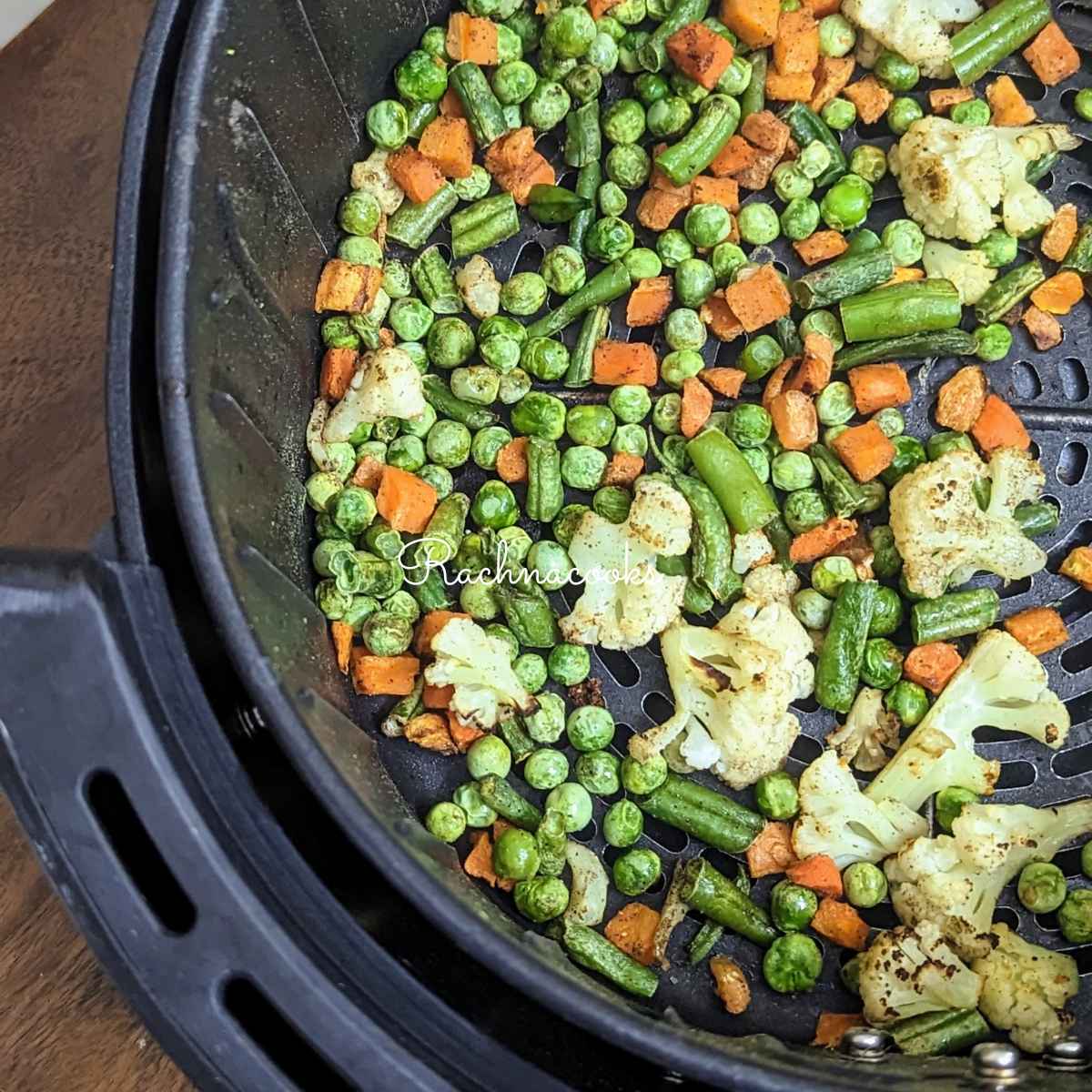 Roasted air fried frozen vegetables in air fryer basket.