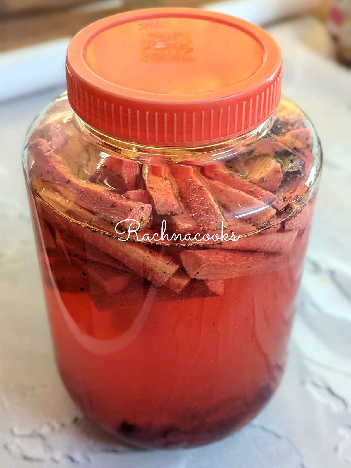 Carrot and beet batons with seasonings, salt and topped up with water in a glass bottle.