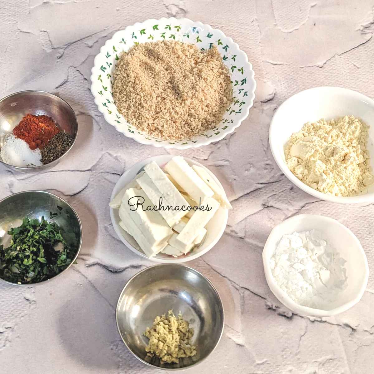 Ingredients for paneer fingers: paneer rectangles, chickpea flour, cornstarch, chopped cilantro, cayenne, Italian seasoning, salt in a bowl, minced ginger in bowls.