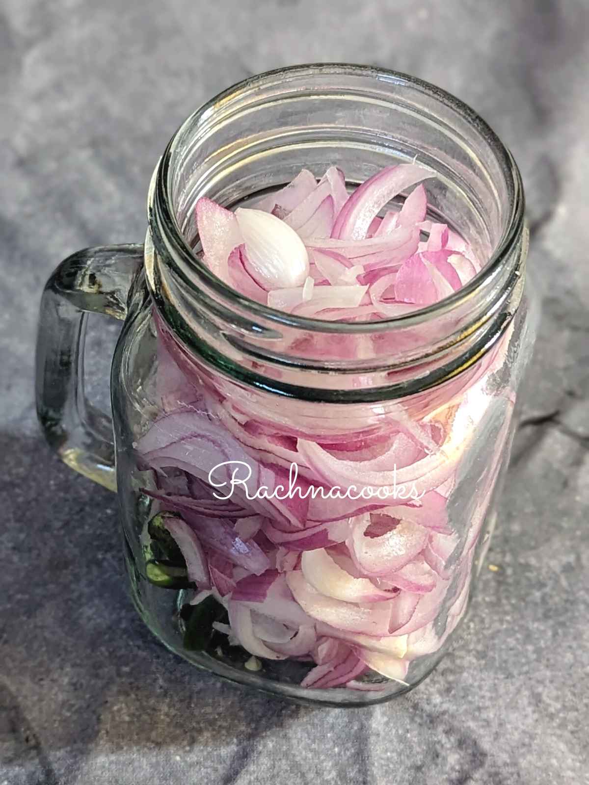 Sliced onion with green chillies in a mason jar.