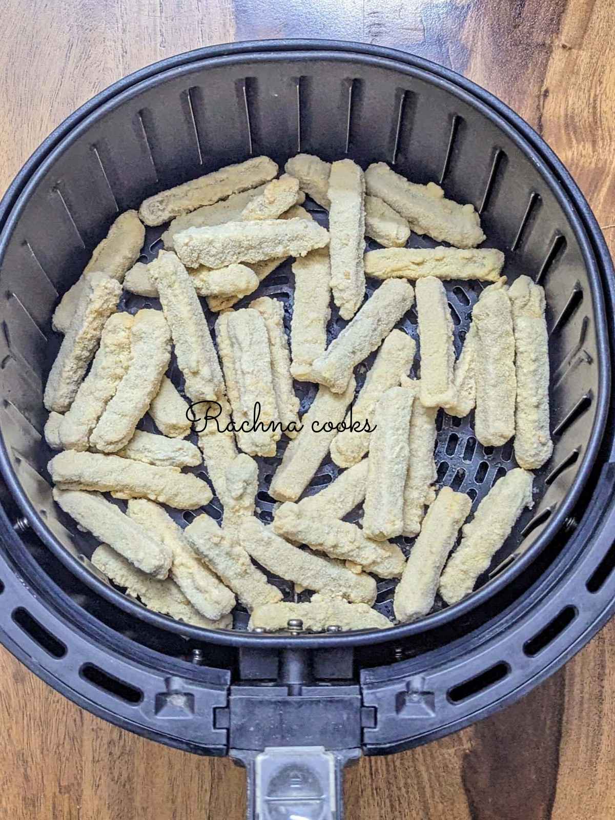 Frozen chicken fries in air fryer basket ready for air frying.