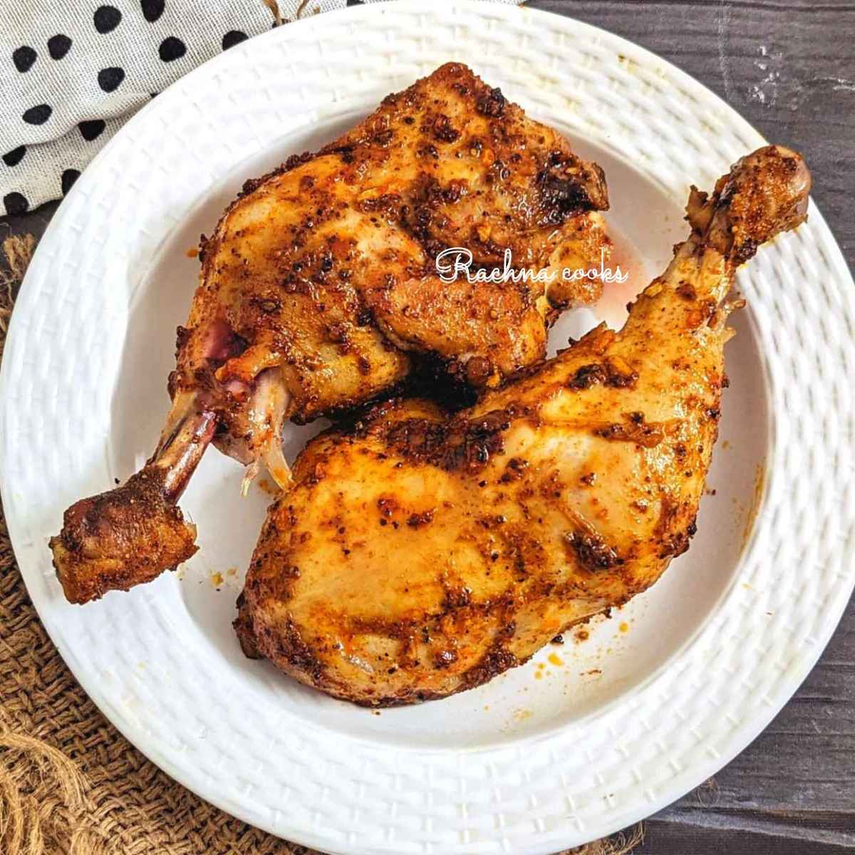 Two chicken leg quarters after air frying served on a white plate.