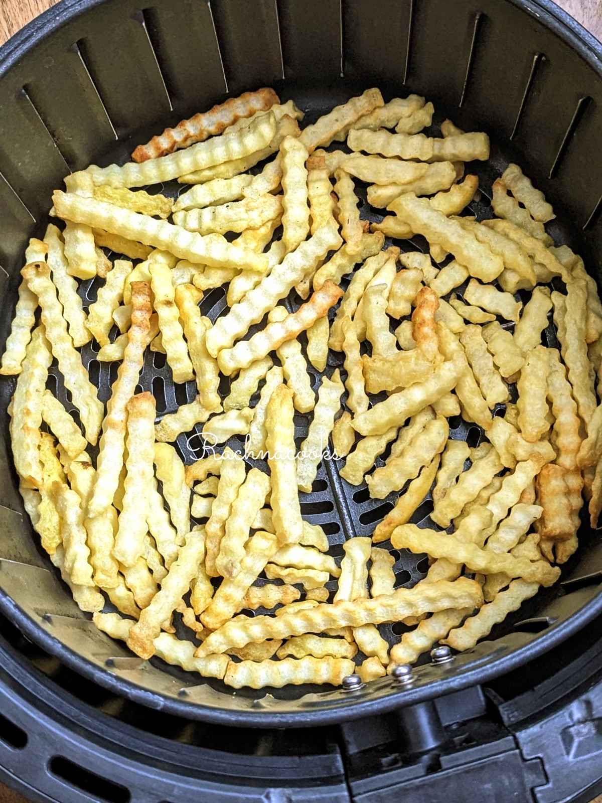 Air fried crinkle cut fries in air fryer basket.