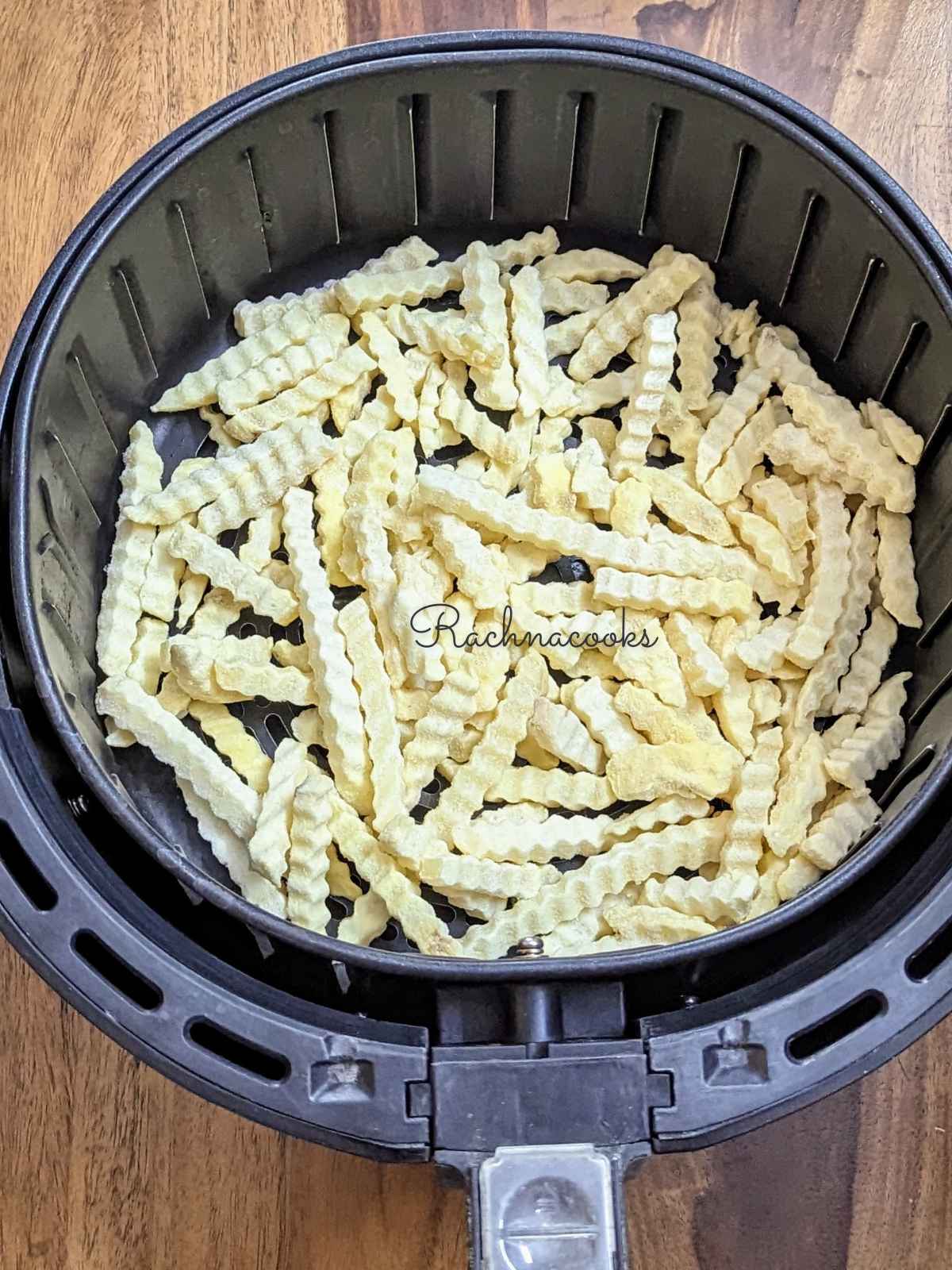 Frozen crinkle cut fries in air fryer basket.