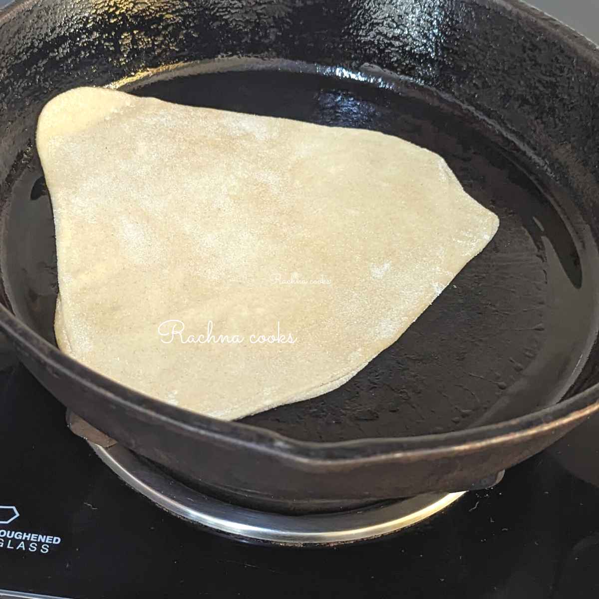 Triangular paratha in a skillet ready for frying.