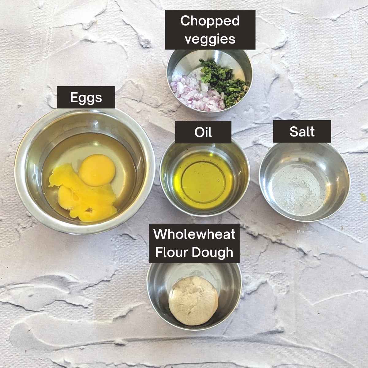 Ingredients to make egg paratha: broken eggs, oil, salt, chopped veggies and wholewheat flour dough.