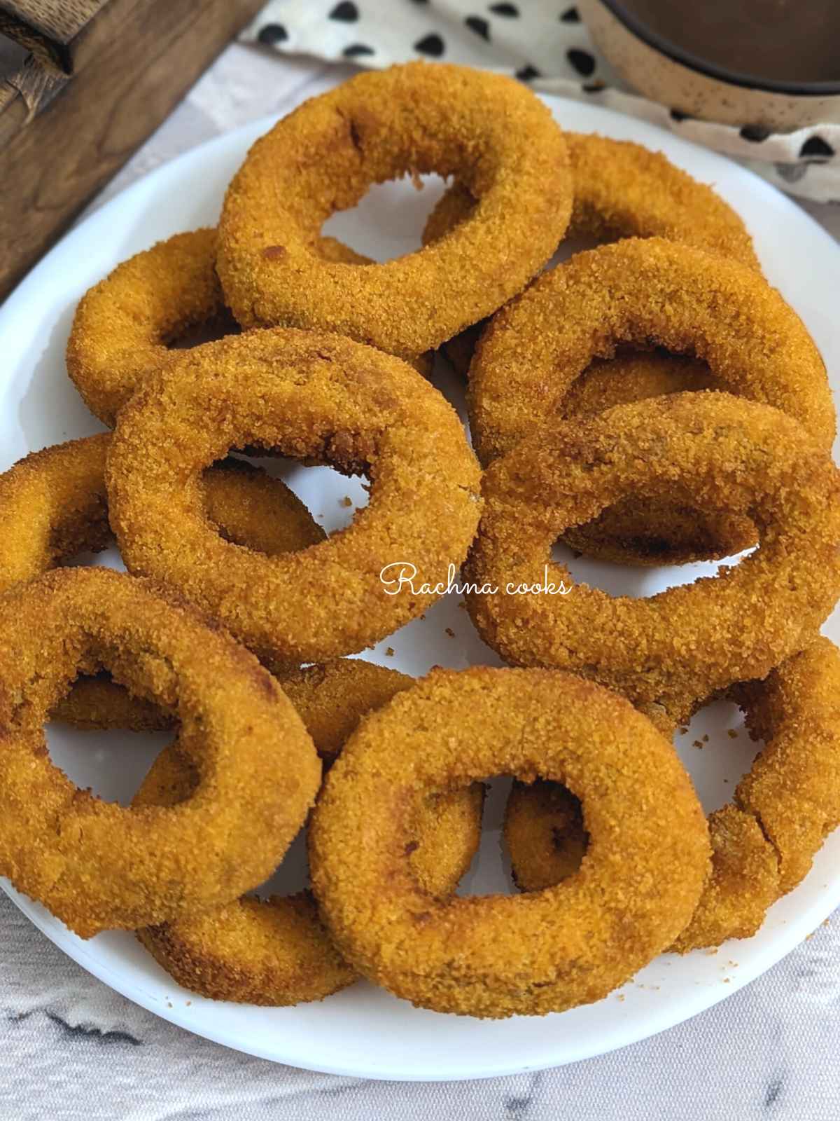 Close up of frozen onion rings done in air fryer and served on a white plate.
