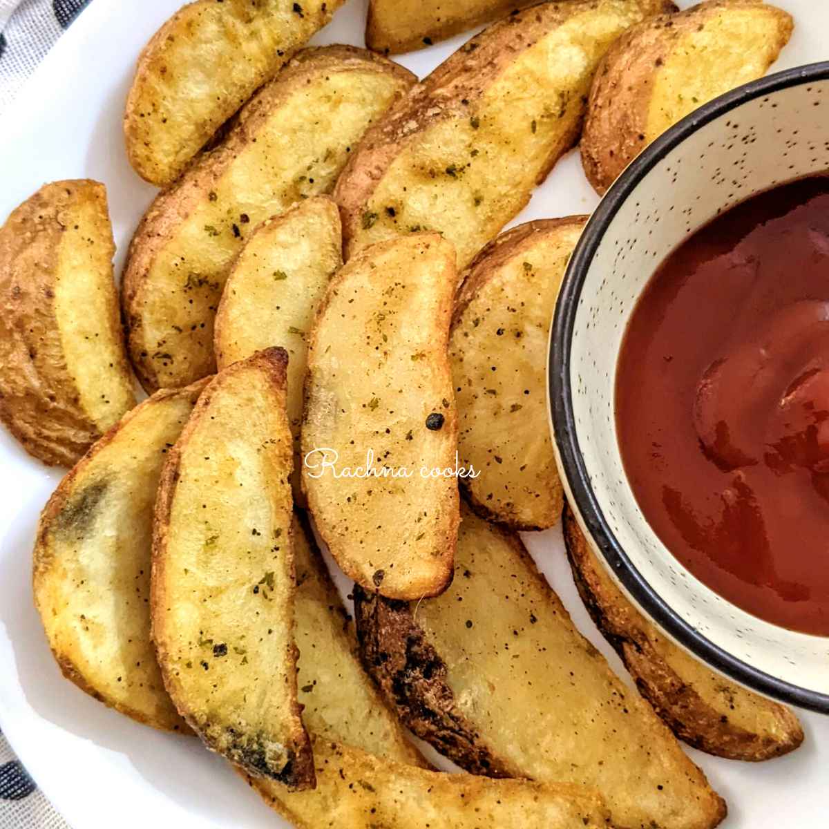Crispy potato wedges served on a white plate with a dip in the bowl.