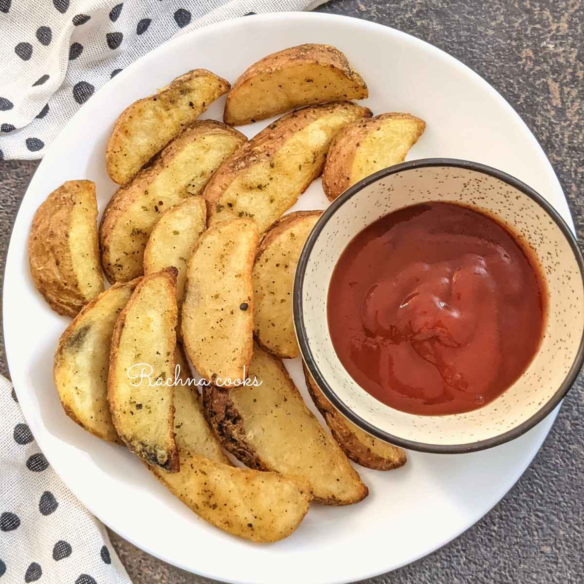 Crispy potato wedges served on a white plate with a dip in the bowl.