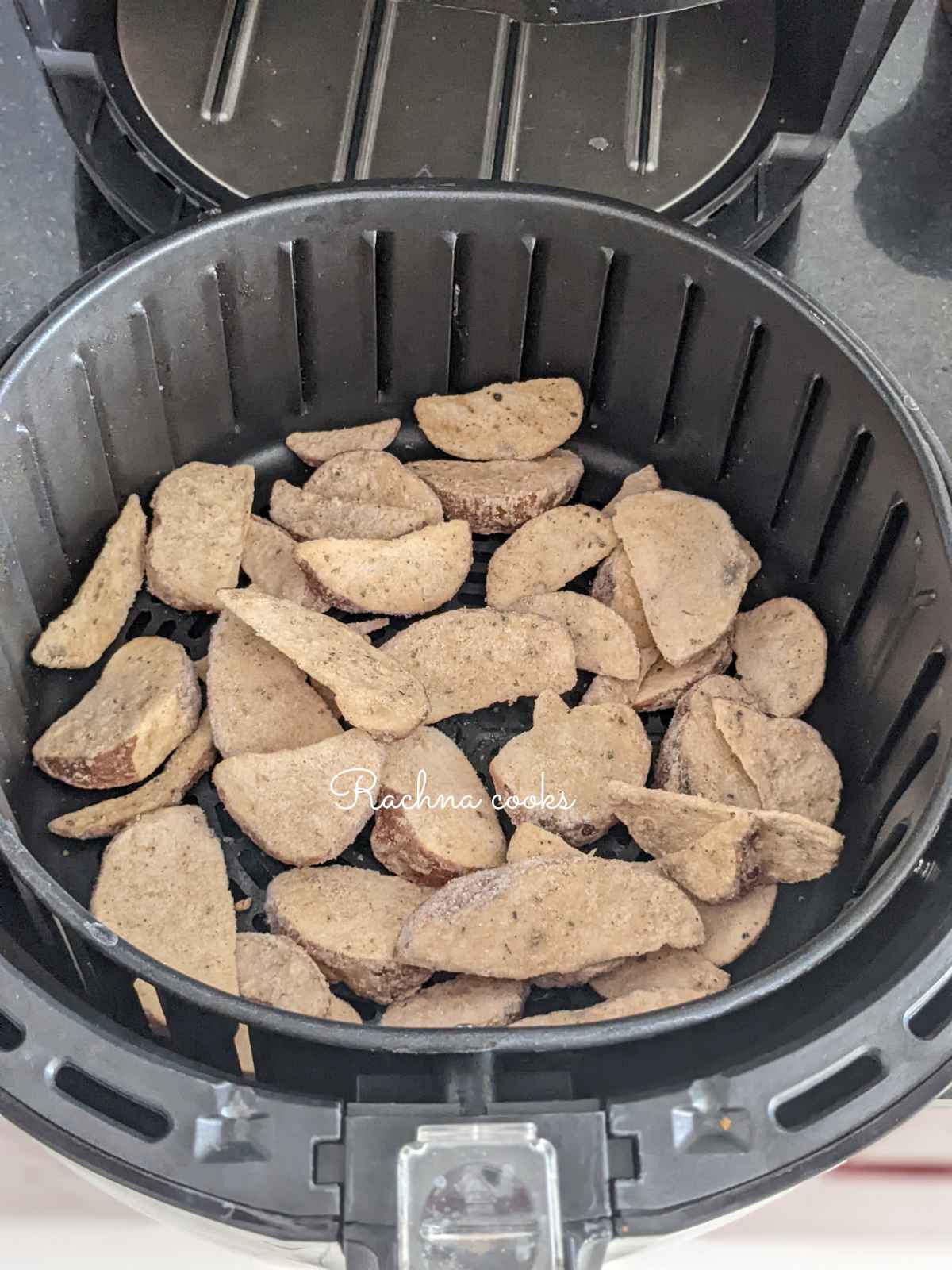 Frozen potato wedges in air fryer basket ready for air frying.