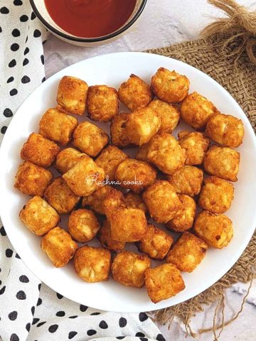 Tater tots on a white plate.