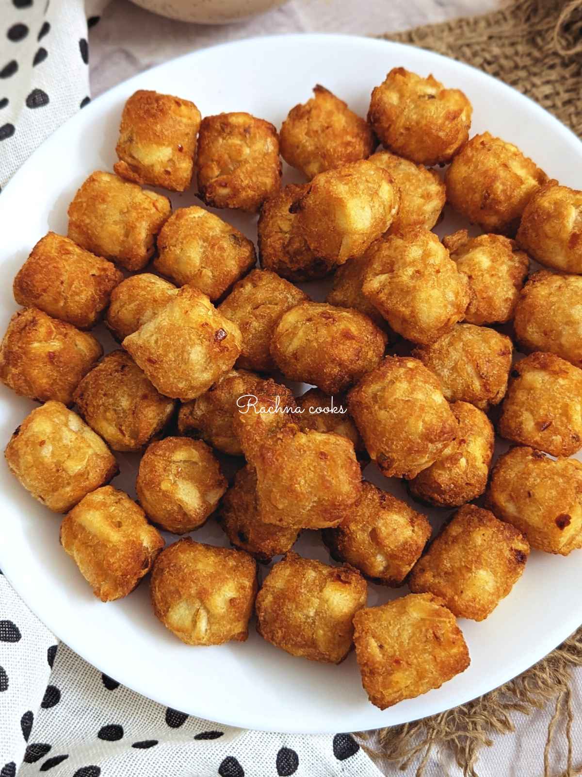 Golden tater tots served on a white plate.