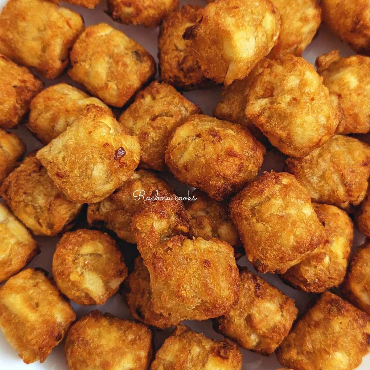 Golden tater tots served on a white plate.