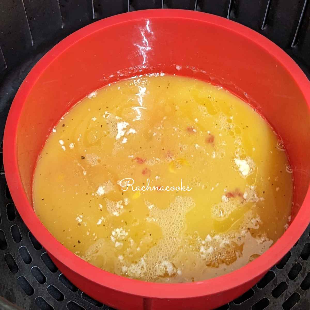 Whisked egg mixture slightly cooked in a mould in air fryer basket.