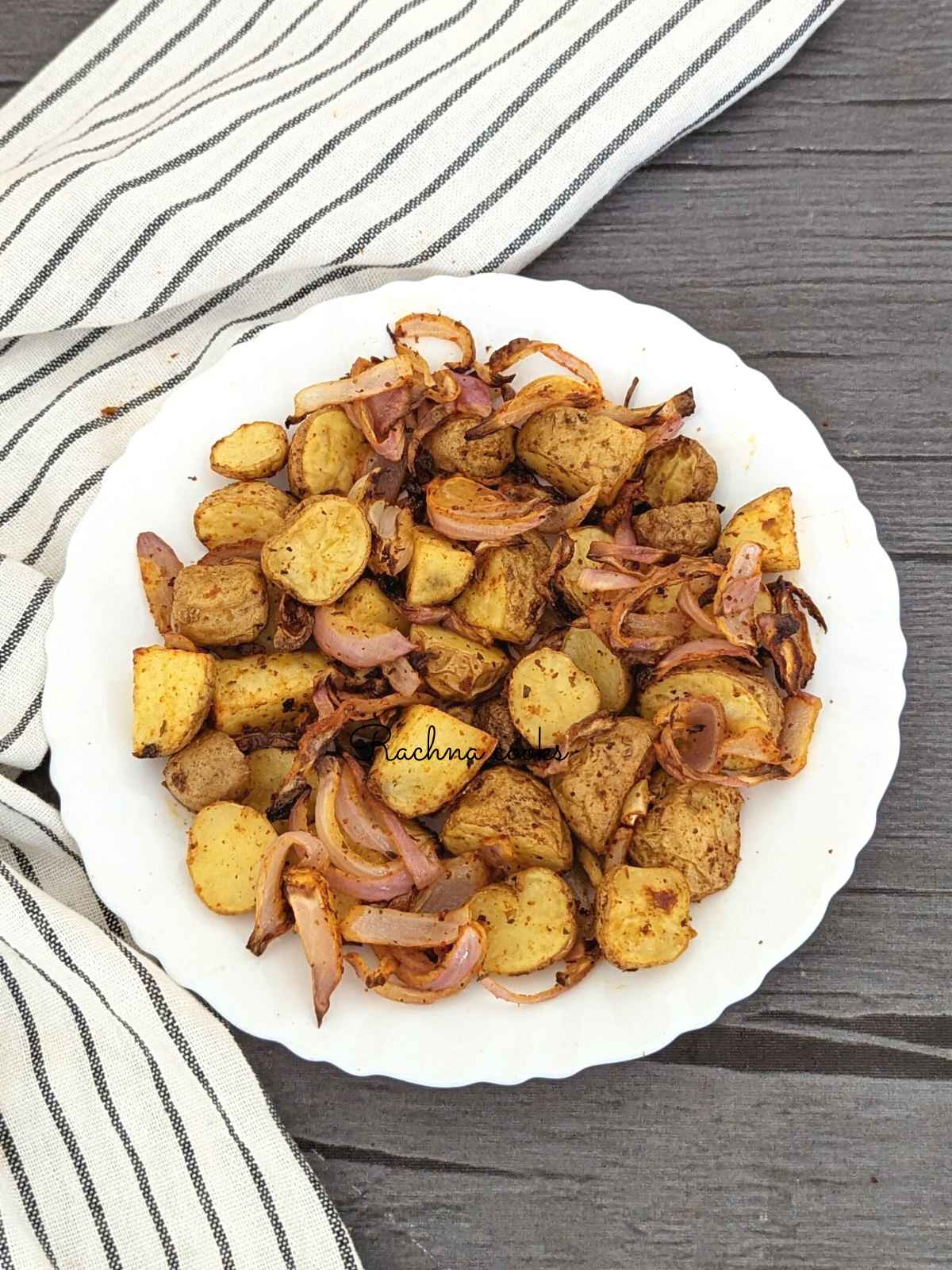 Crispy air fried potatoes and onions served on a white plate.