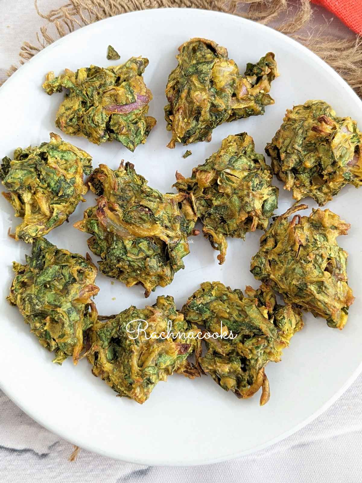A plate of 10 spinach pakoras on a white plate.