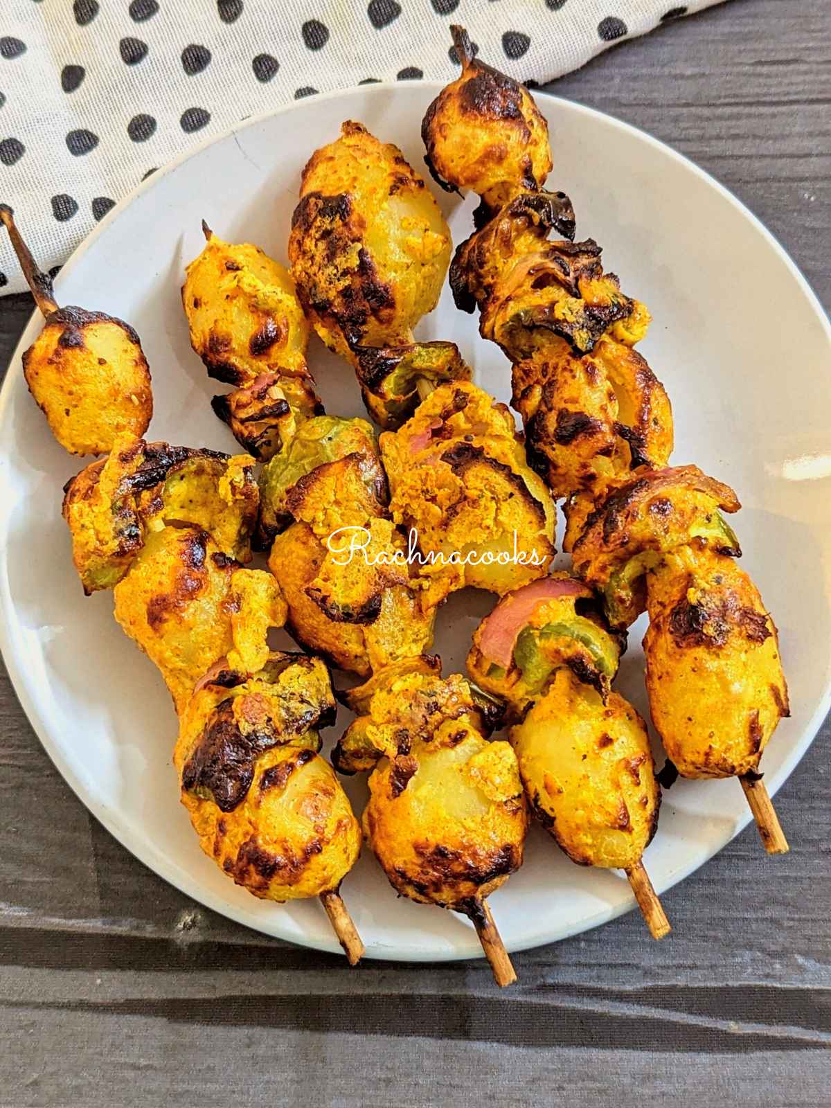 4 skewers of marinated potatoes, pepper and onion after air frying served on a white plate.