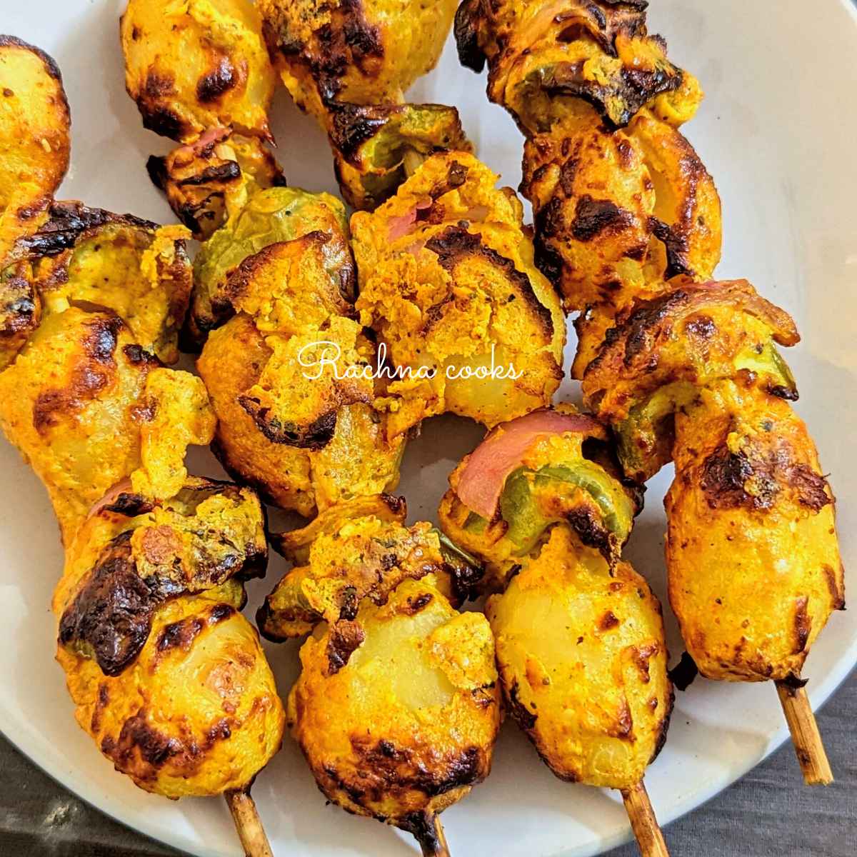 4 skewers of tandoori aloo on a white plate