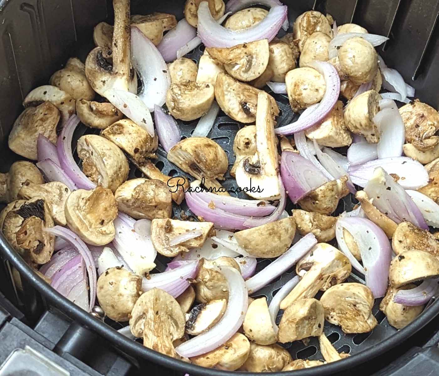 Mushrooms and onions in air fryer basket.