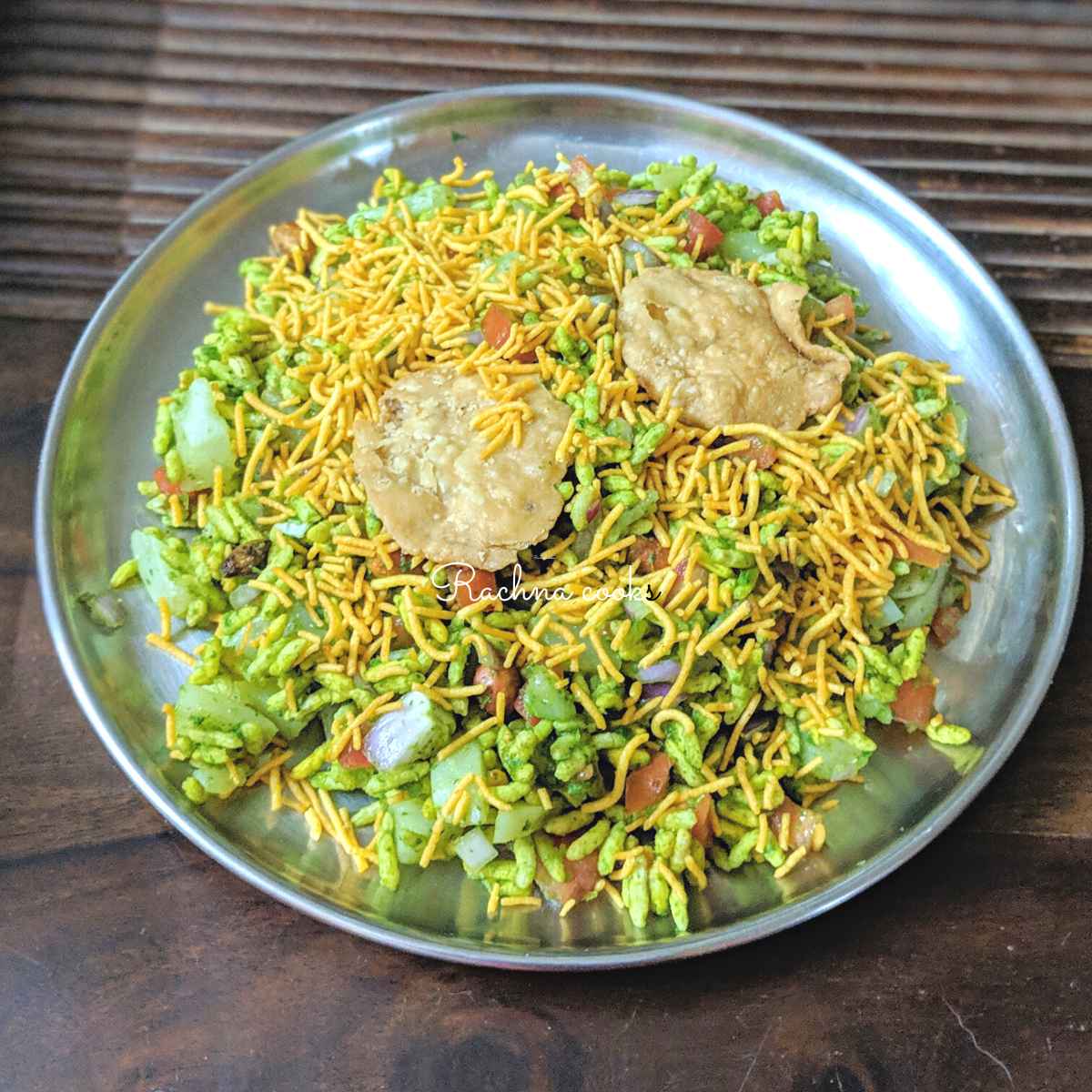 Bhel puri served in a plate with papdi topping.
