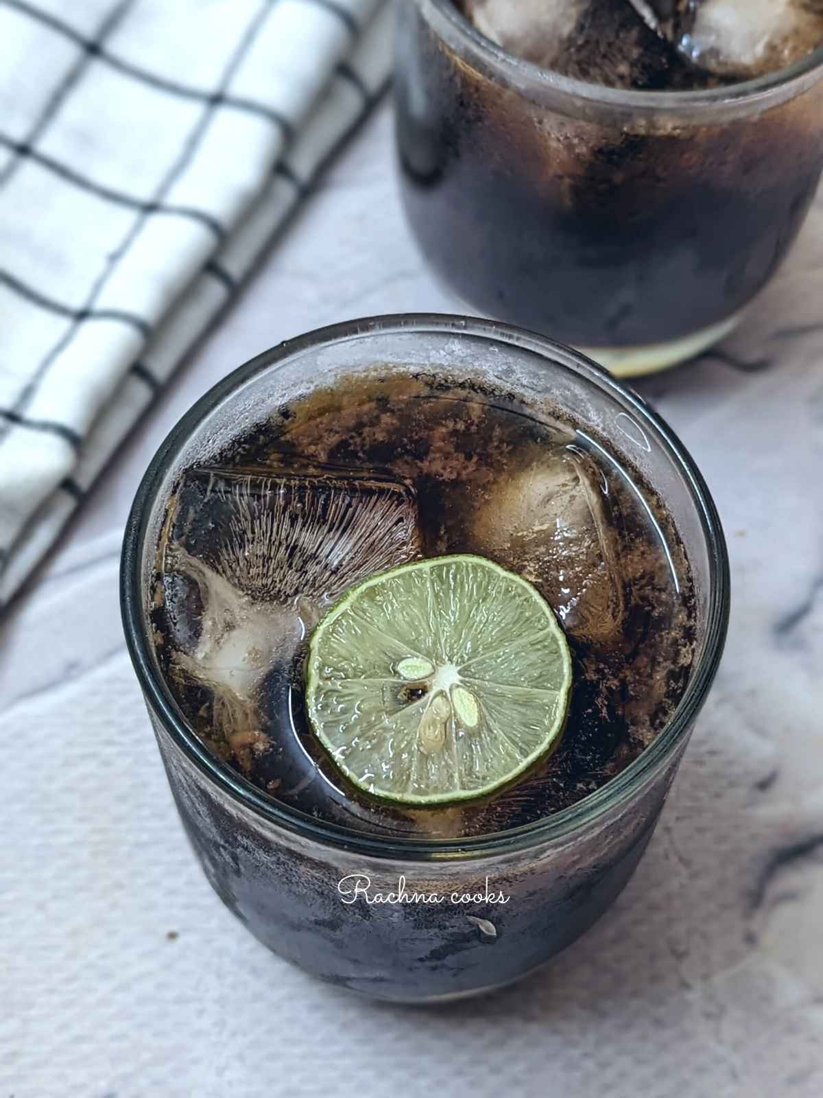 A glass of brown sugar lemonade with a wedge of lime and ice cubes