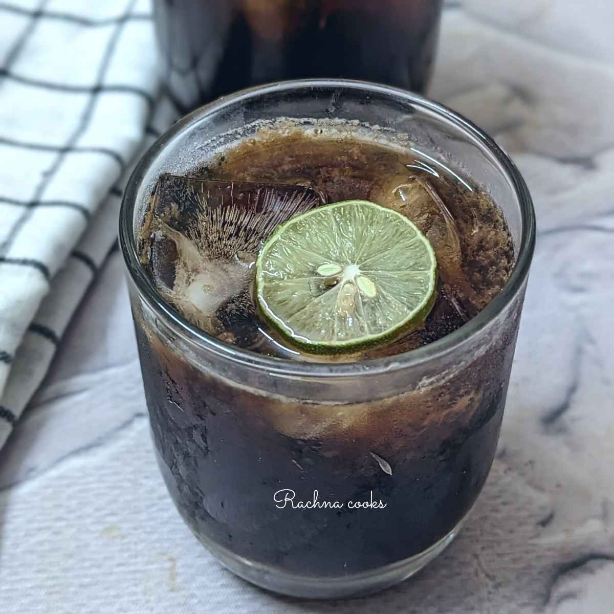 A glass of brown sugar lemonade with a wedge of lime and ice cubes
