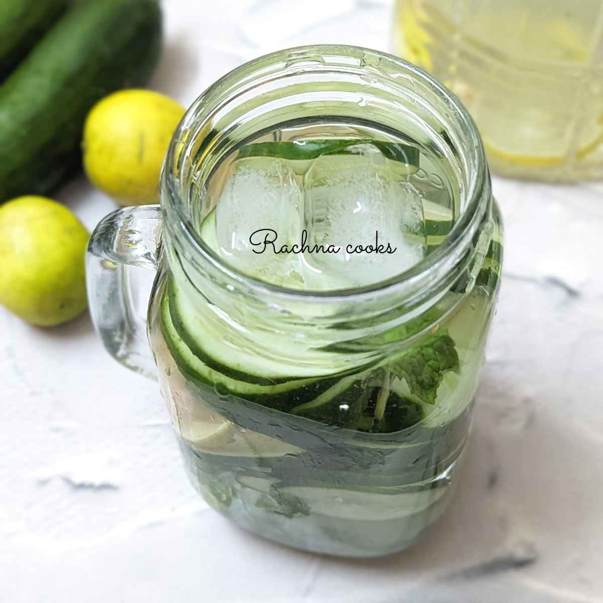 Lemon cucumber ginger water topped with ice cubes served in a mason jar.