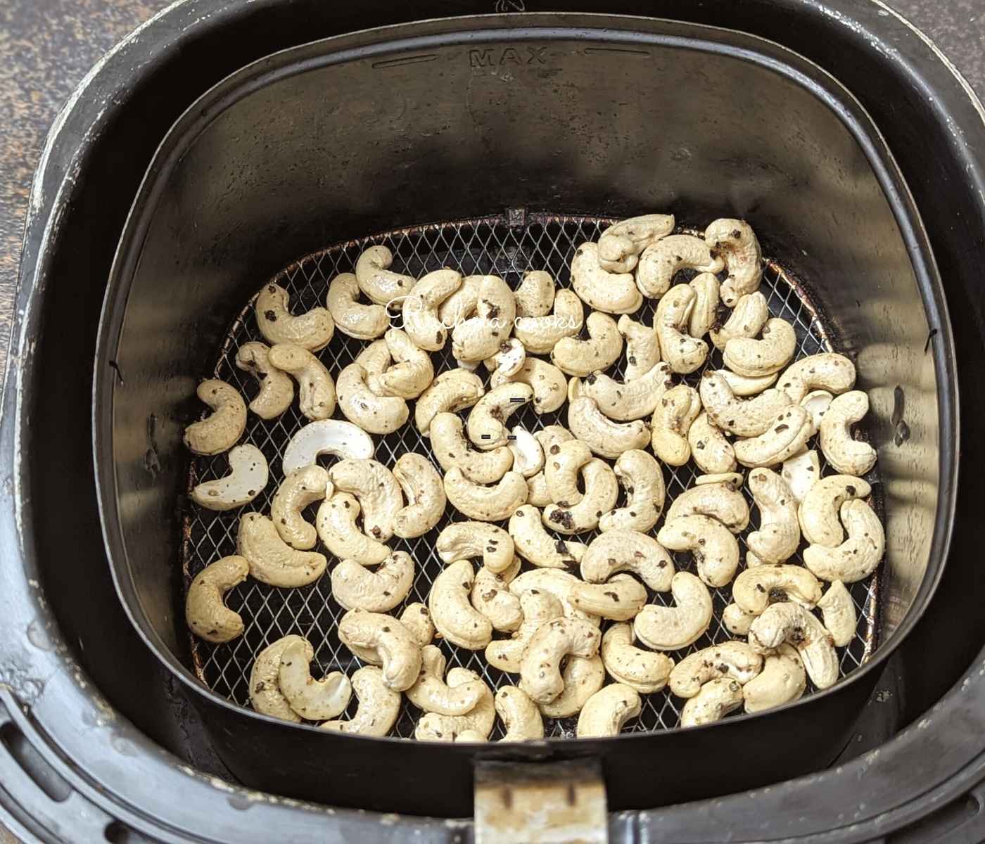 Cashews placed in air fryer basket.