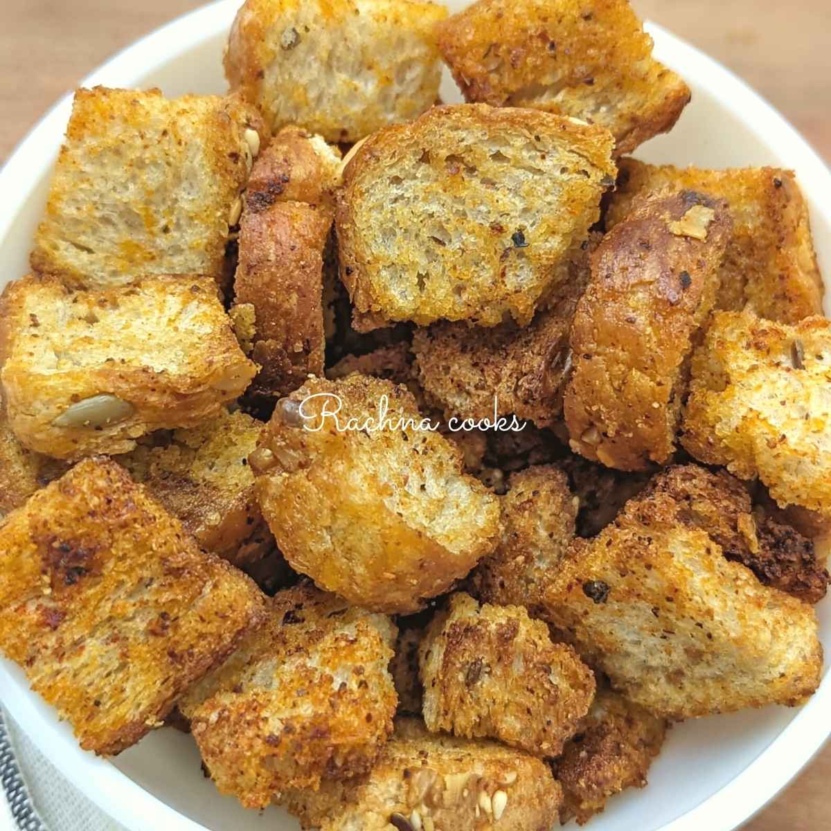Golden air fried croutons in a white bowl