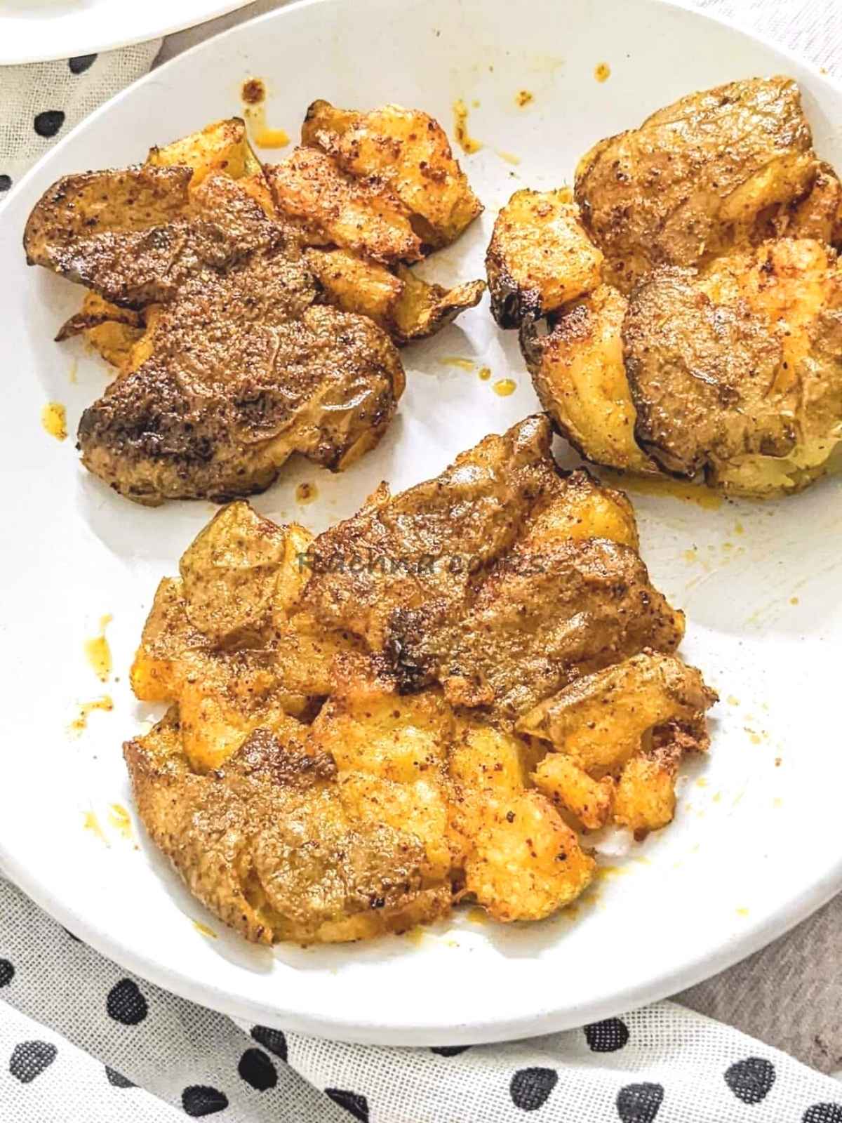 3 smashed air fryer potatoes served on a plate.