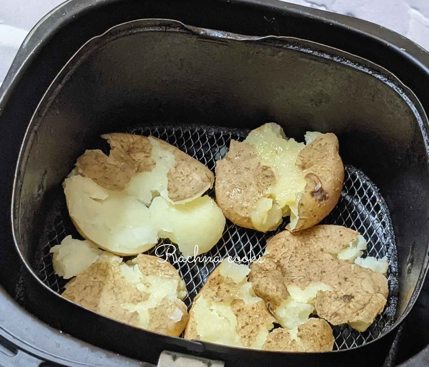 Smashed potatoes placed in air fryer basket for air frying.