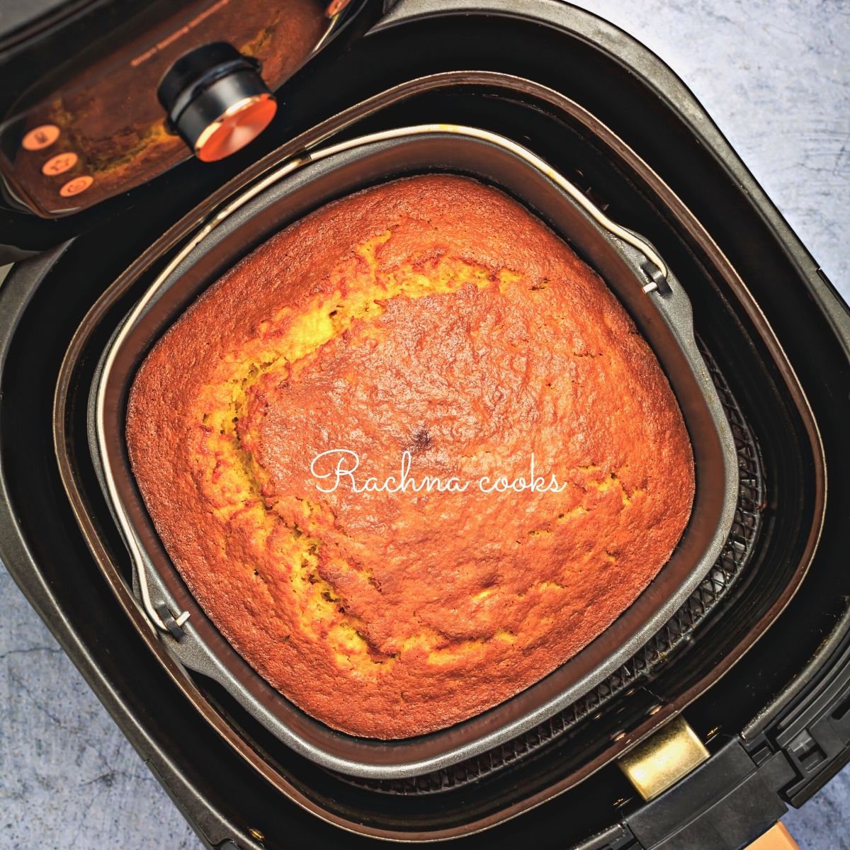 A metal baking container with cake inside an air fryer basket.