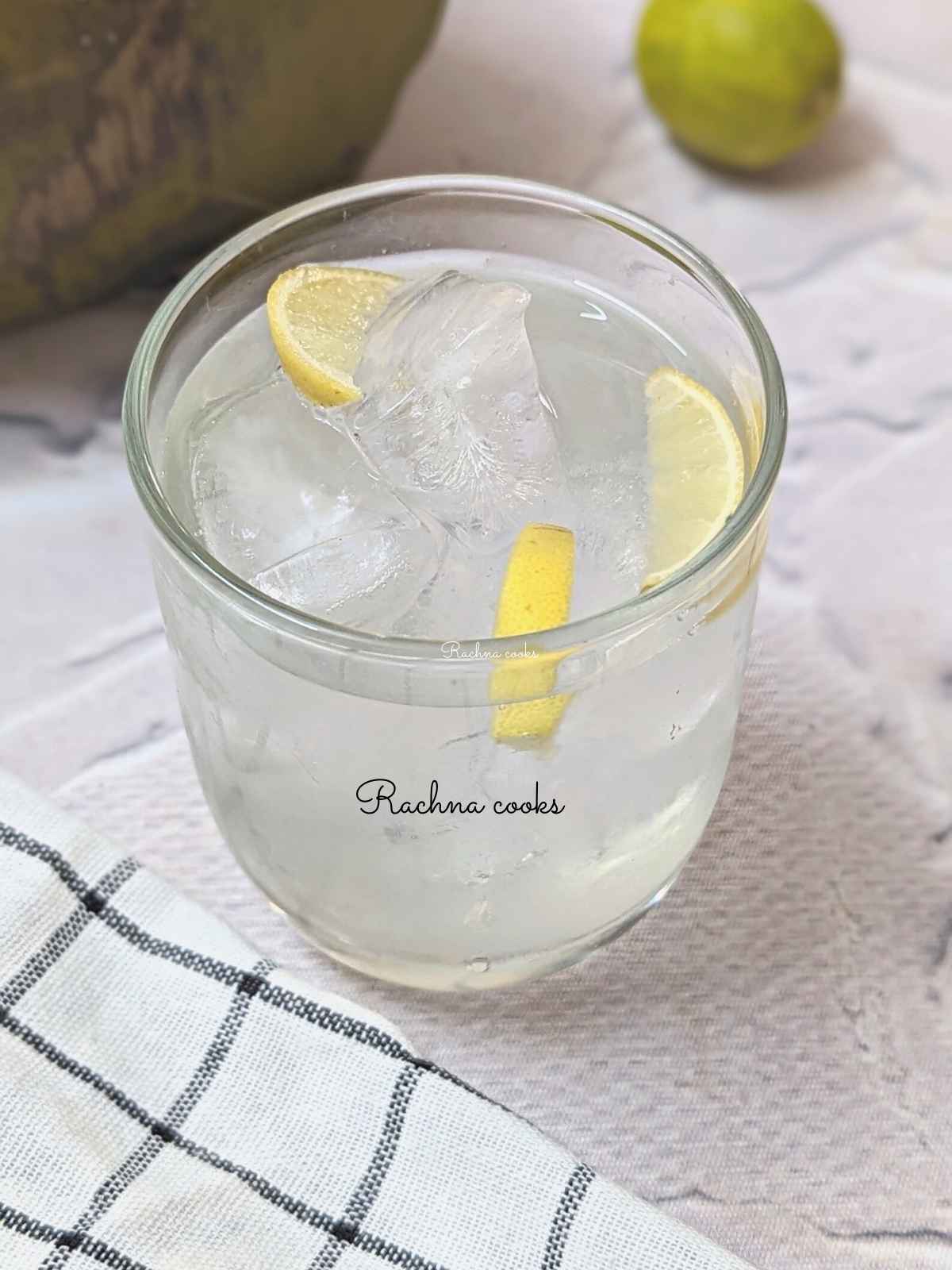 A glass of coconut water lemonade with lemon wedges.