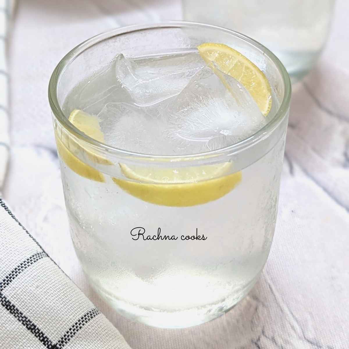 A glass of coconut water lemonade with lemon wedges.