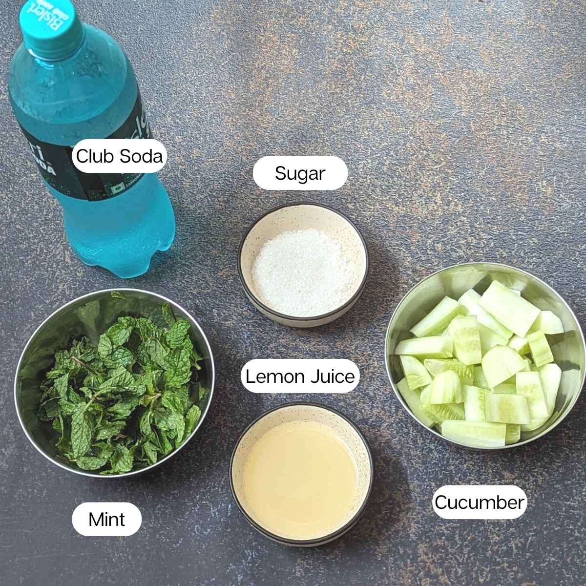 Ingredients for making cucumber mint lemonade: club soda, mint, cucumber cubes, lemon juice, sigar.