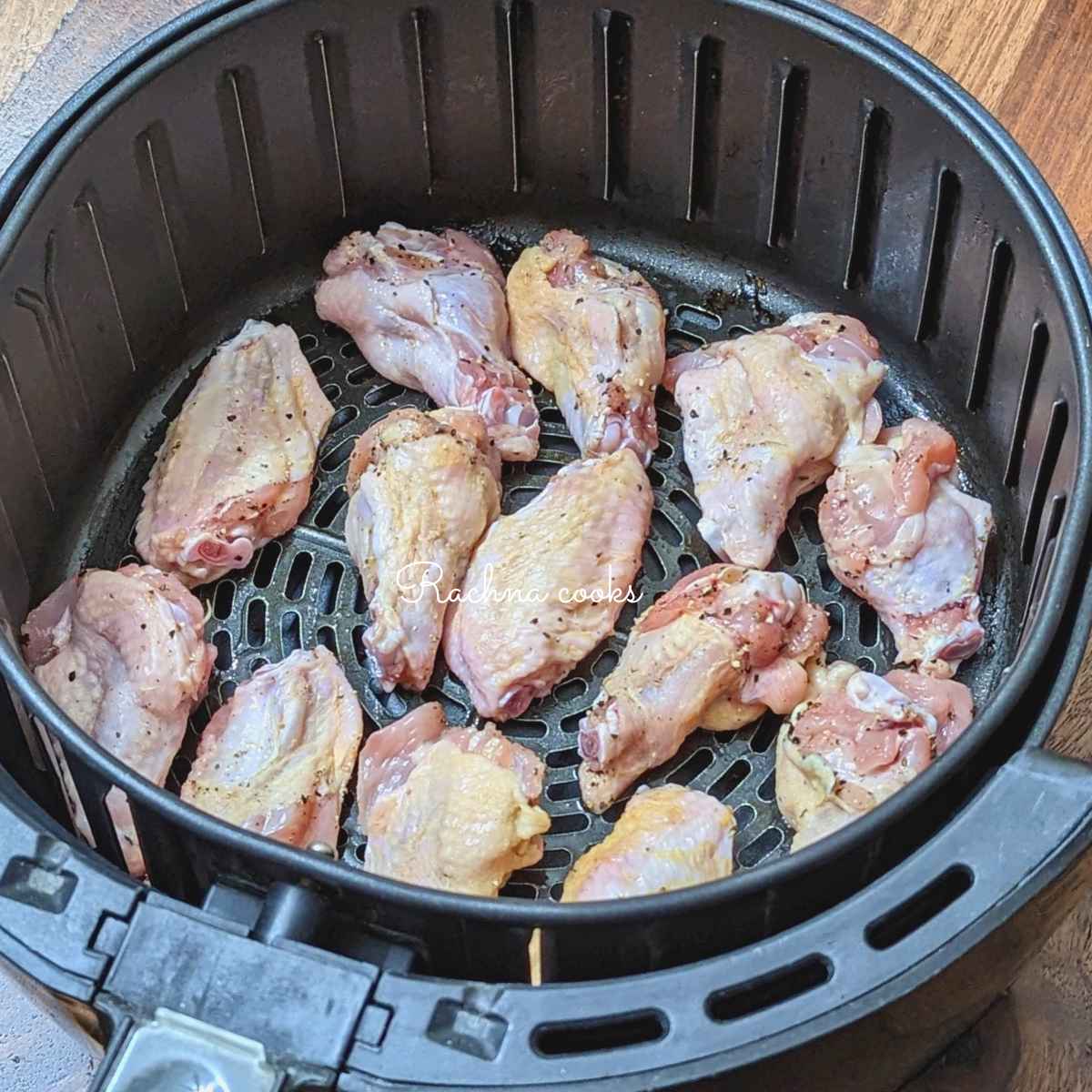 Seasoned chicken wings in air fryer basket