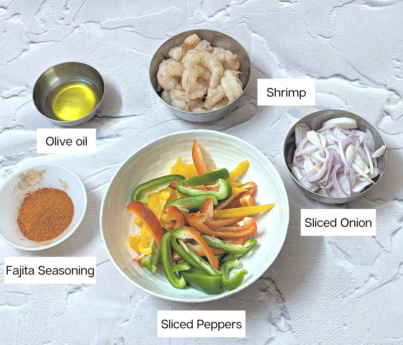 Ingredients for making shrimp fajitas: shrimp, sliced onion, peppers, olive oil and fajita seasoning.
