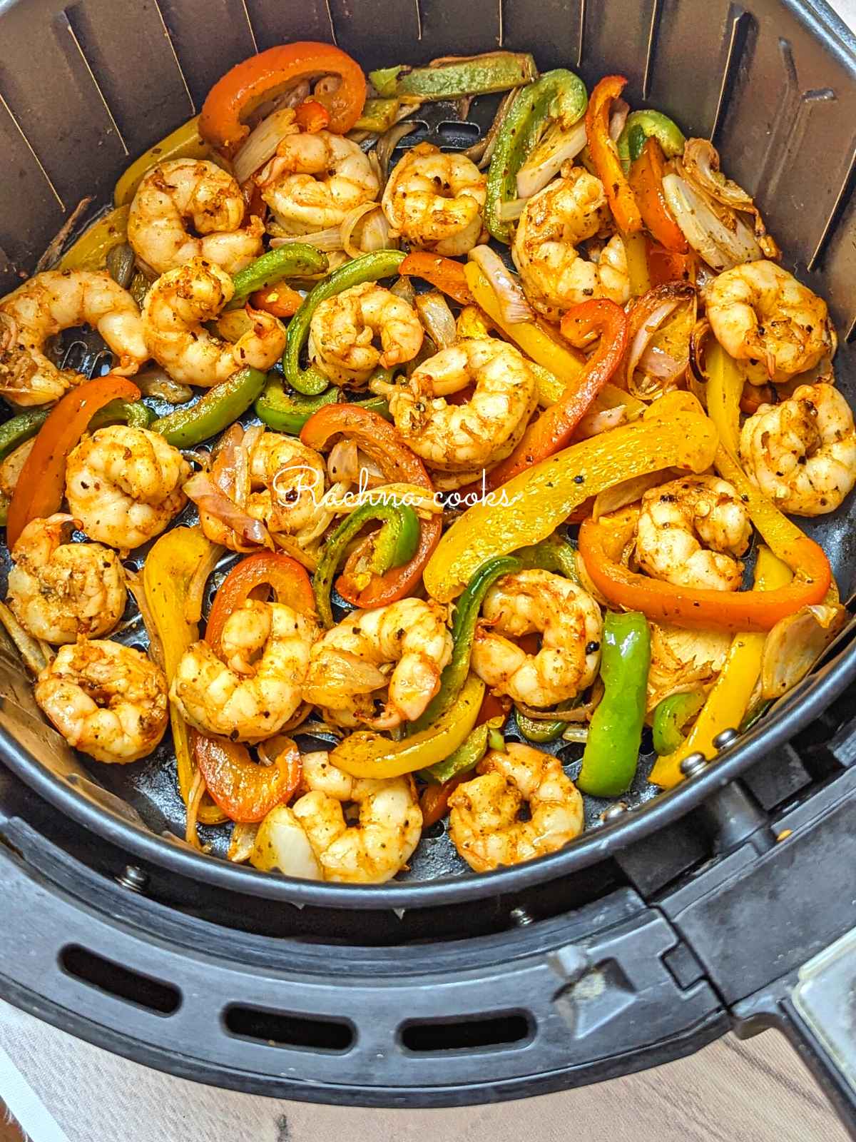 Shrimp and veggies after air frying in air fryer basket.