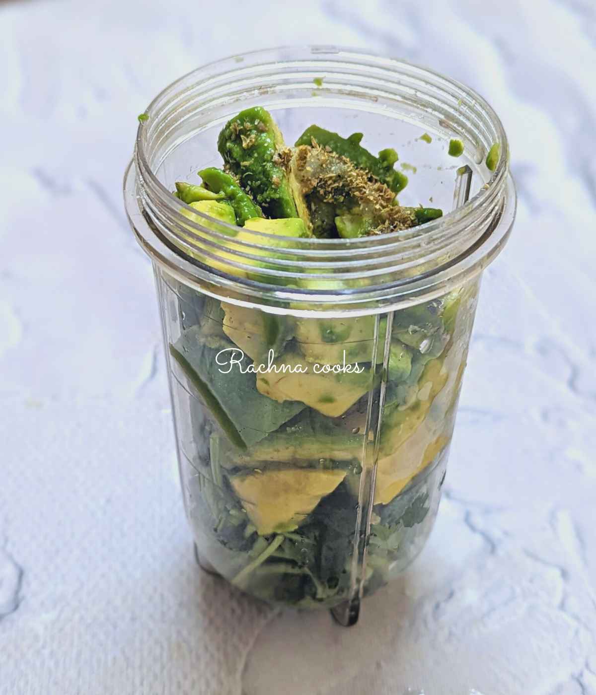 Blender jar with chopped avocado, cilantro, garlic, chillies, lemon juice, salt and seasonings.