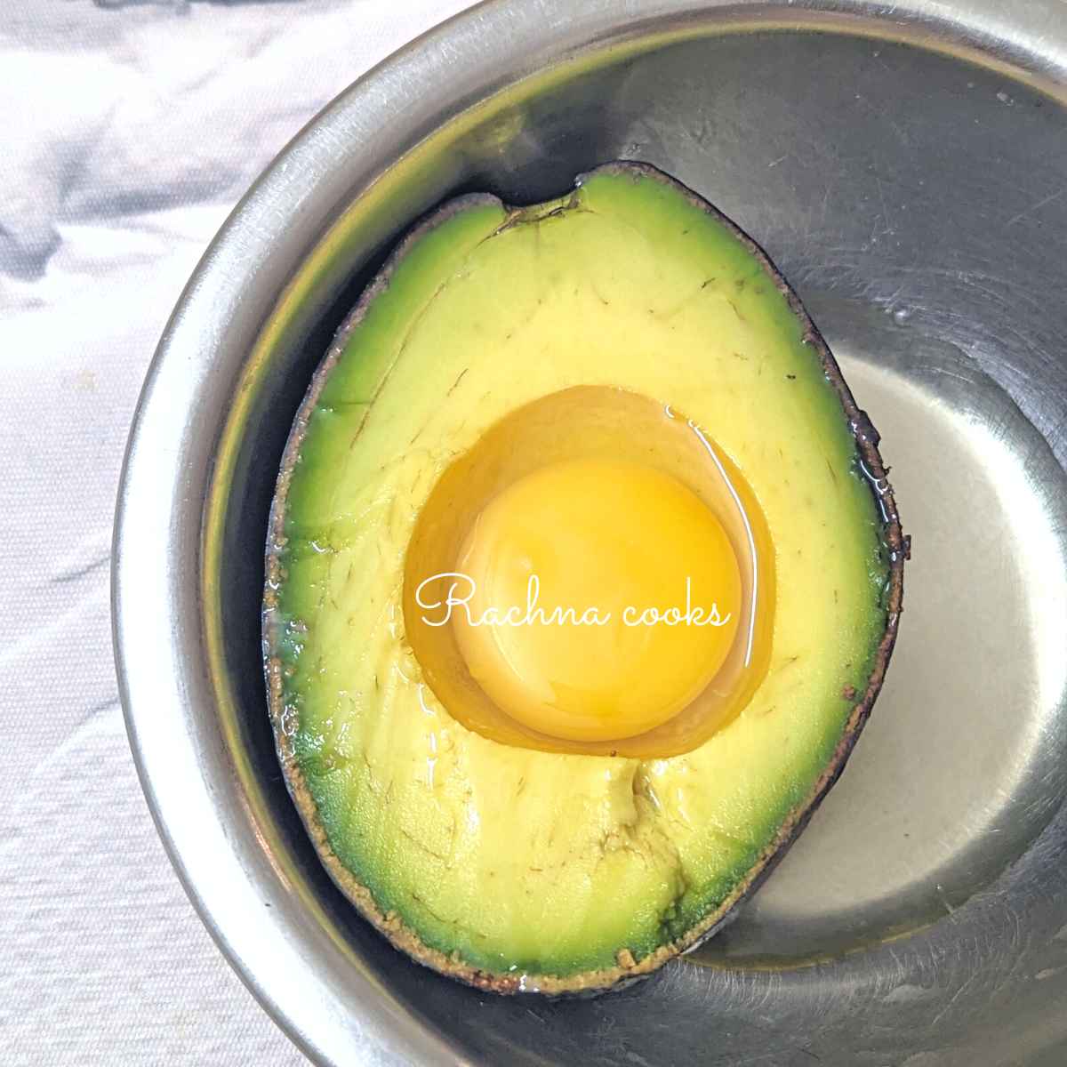 Half of an avocado with yolk and white in the cavity.