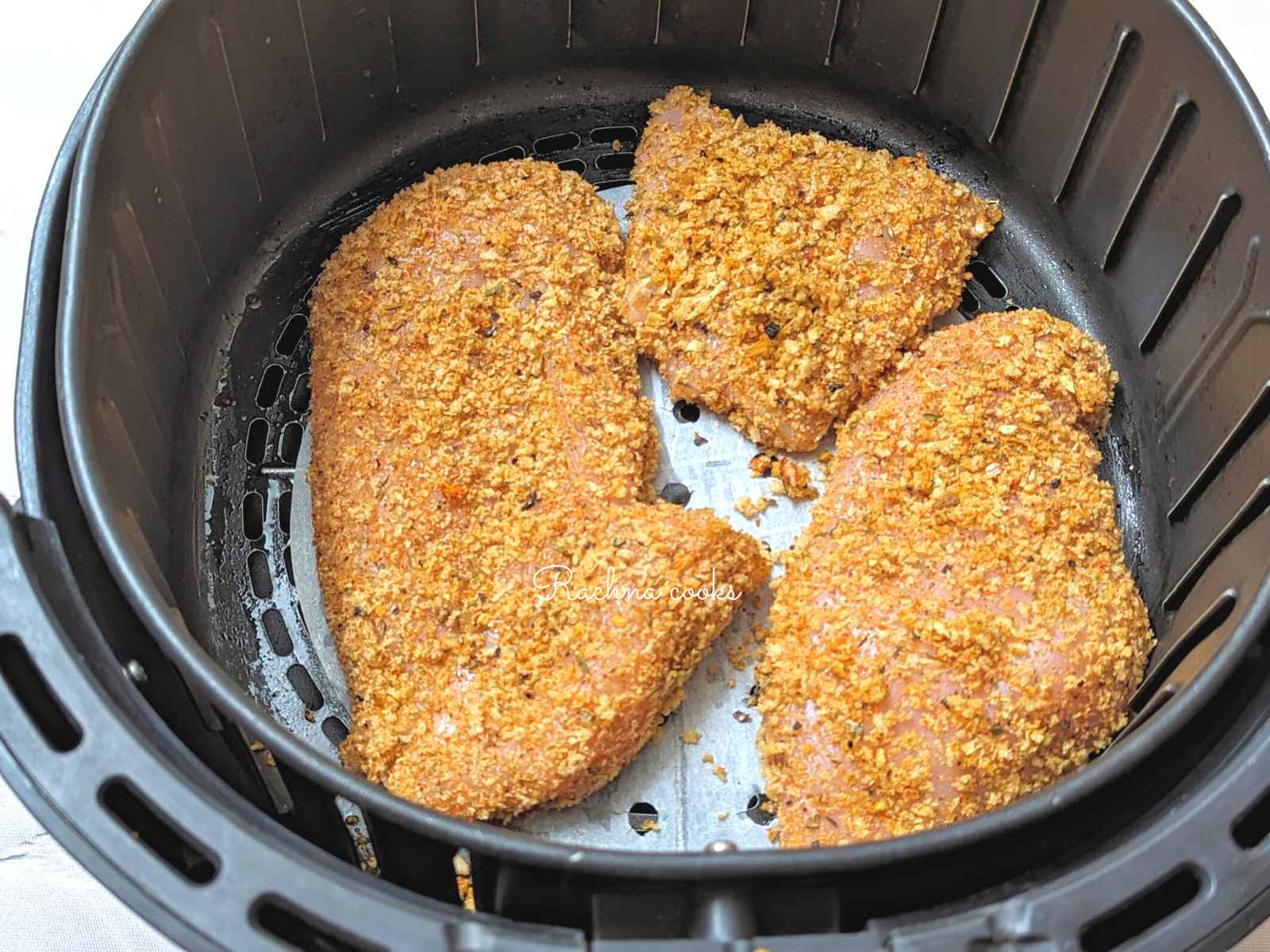 Breaded shake and bake breasts placed jn air fryer basket.