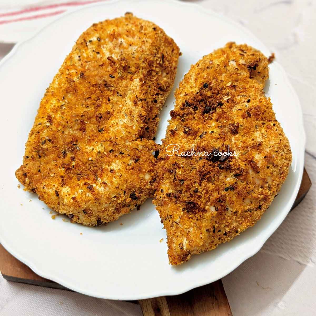 2 shake and bake chicken breasts on a white plate.