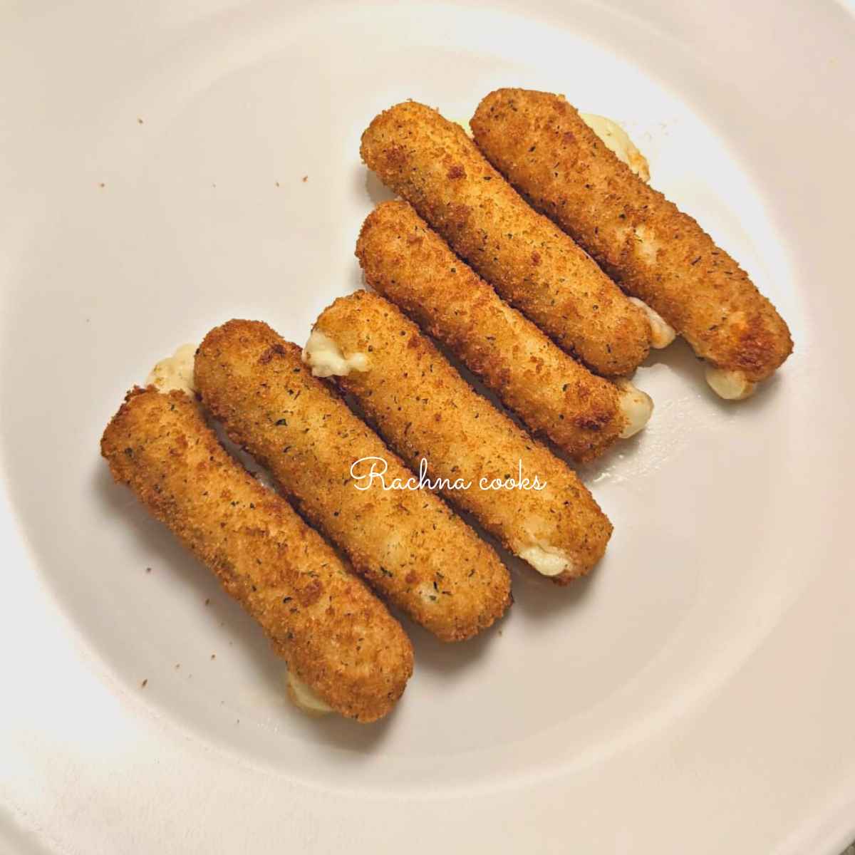 Mozzarella sticks after air frying served on a white plate.
