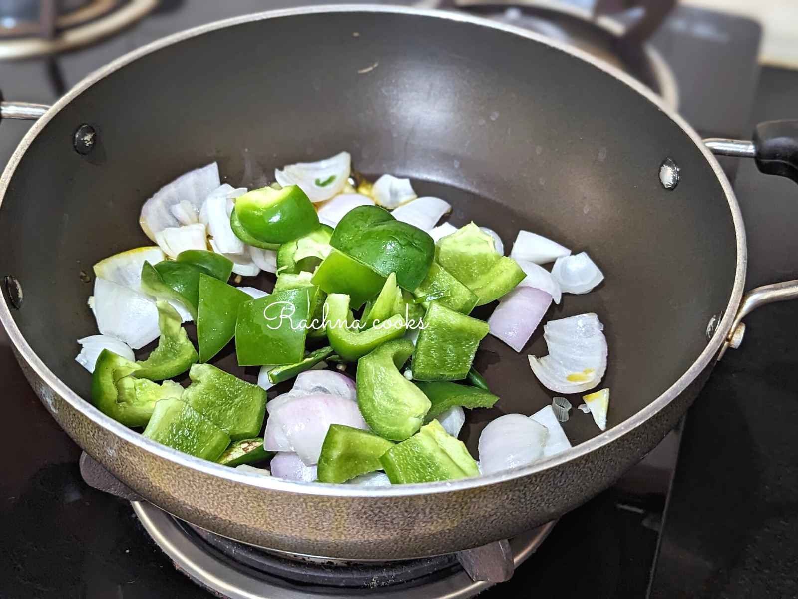 Onion and green pepper cubes sauteed in a pan.